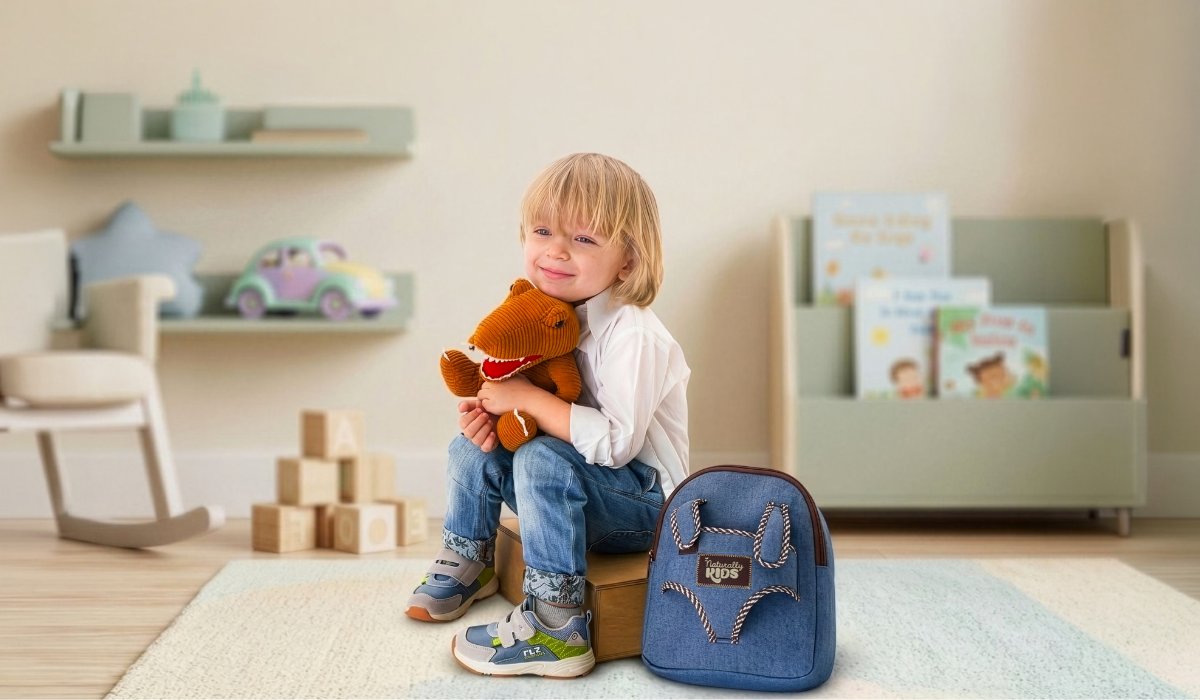 Naturally KIDS plush brown T-Rex held by a three-year-old boy, his dinosaur backpack behind him