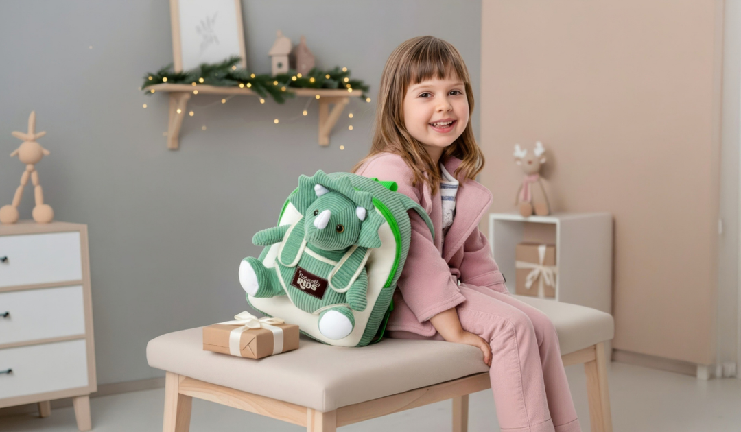 Naturally KIDS small backpack with a removable green corduroy plush triceratops, next to a kraft gift box in a room decorated for the holidays