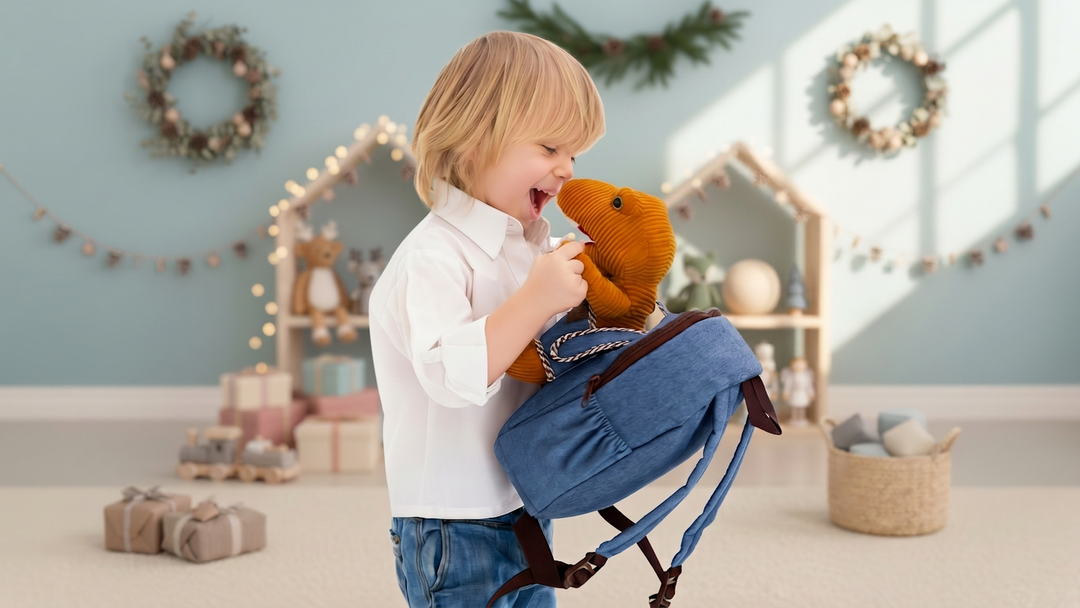 A toddler laughs and hugs the corduroy plush T-Rex on a Naturally KIDS small backpack in a room decorated for Christmas